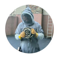 Derrek in a protective bee suit holding a hornet nest